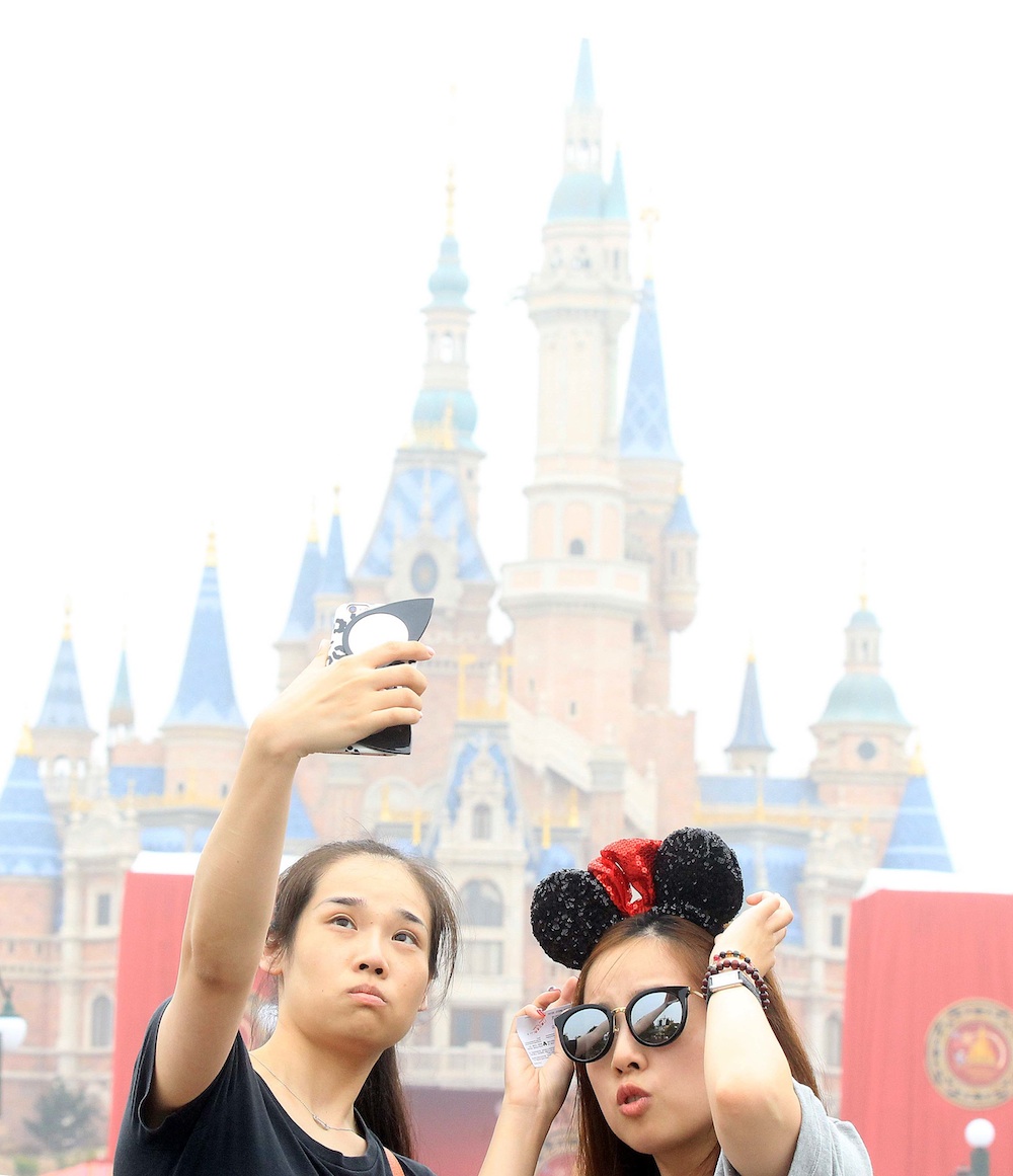 SHANGHAI, CHINA - JUNE 16: Tourists take a selfie at Shanghai Disney Resort on June 16, 2016 in Shanghai, China. Shanghai Disney Resort held the opening ceremony and welcomed tourists on Thursday. (Photo by Visual China/Getty Images)